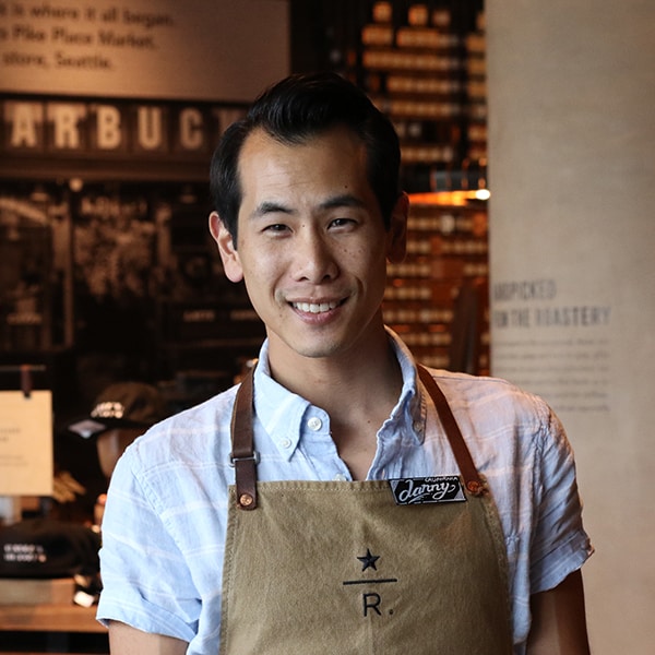 Male employee smiling wearing brown roastery apron